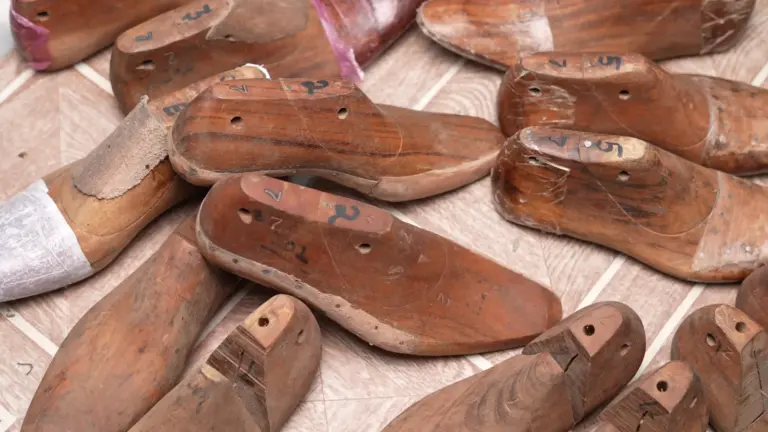 Collection of hand-carved vintage wooden shoe lasts with sizing marks scattered in workshop