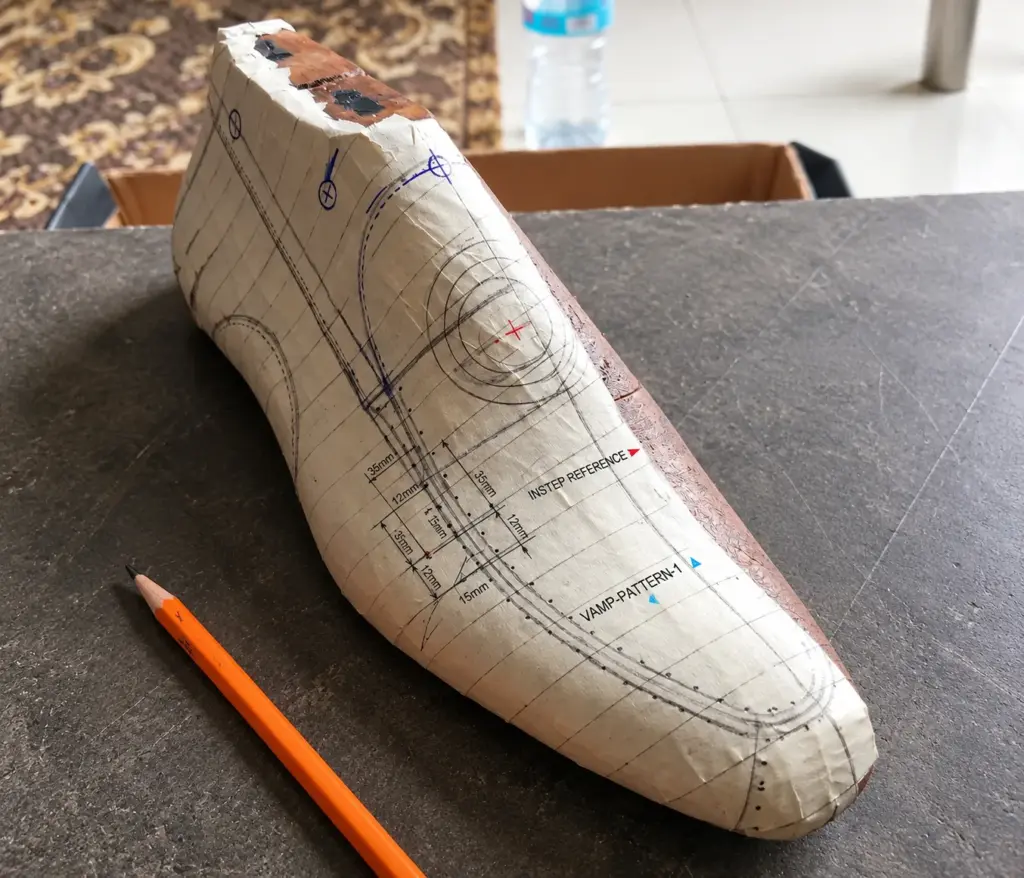 Pattern master drafting bespoke shoe blueprint on paper for custom handmade shoe