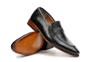 Angled view of black leather loafers showing upper and warm brown outsole