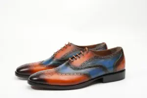 Angled pair view of cognac and blue patina full brogue Oxford shoes
