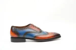 Side profile of cognac-blue patina wingtip Oxford shoe