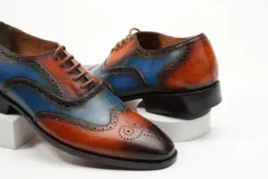 Close view of cognac-blue patina wingtip Oxford shoes showing brogue perforations