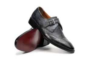 Angled view of grey-black monk strap shoes showing red-brown outsole