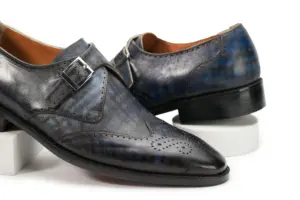 Close view of grey-black patina single monk shoes showing wingtip seam and buckle
