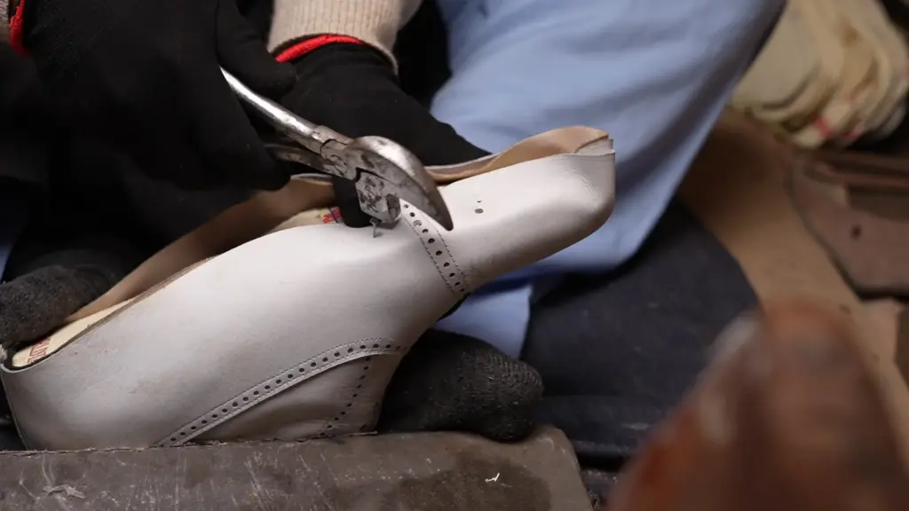 Expert craftsman attaching full-grain leather insole to shoe last by hand