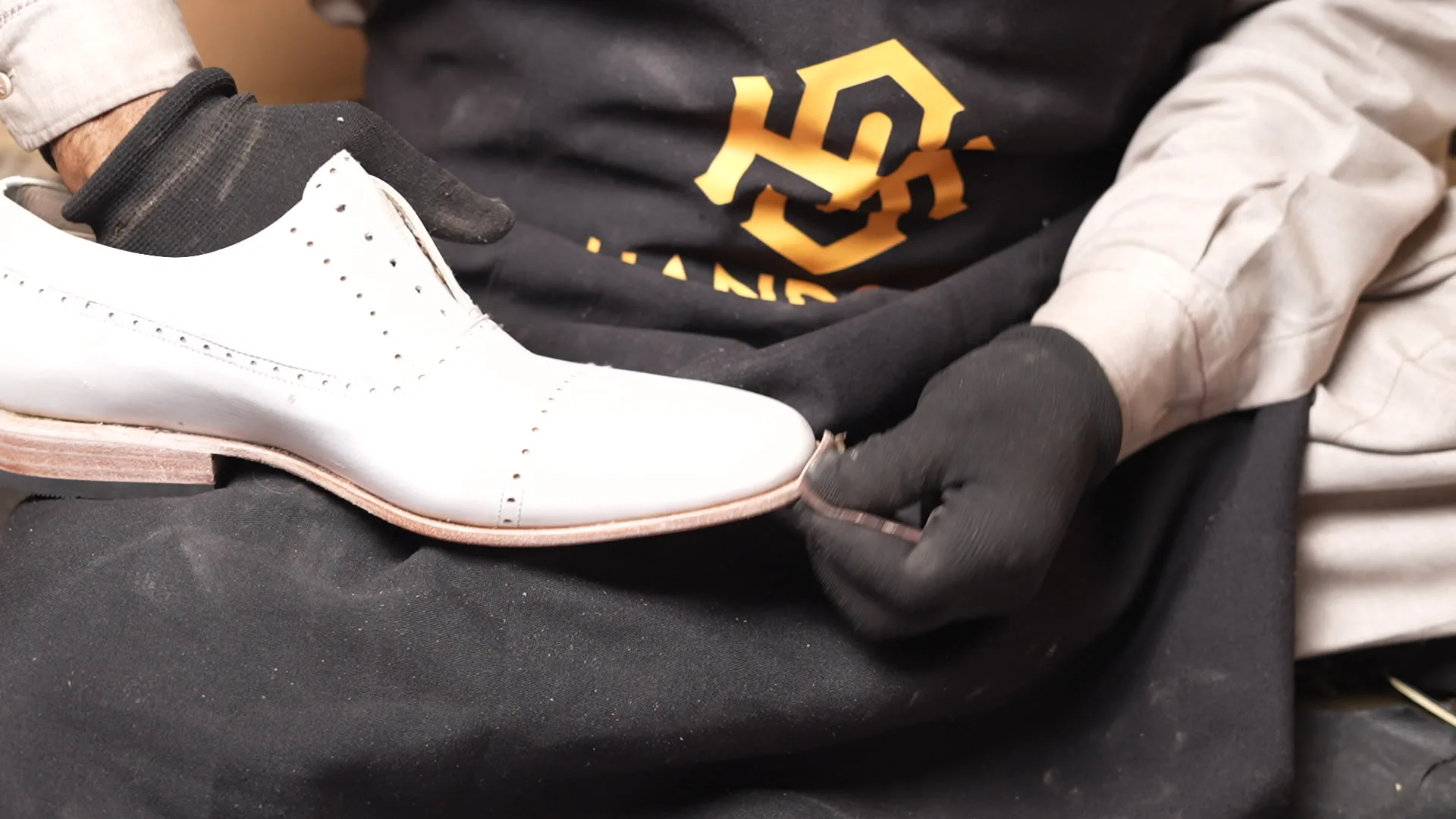 Handsole workshop finishing the edge of a leather shoe sole and heel