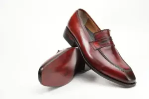 Angled view of red-burgundy penny loafers showing the upper and sole