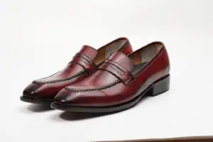 Pair of red-burgundy patina penny loafers showing stitched apron and penny straps