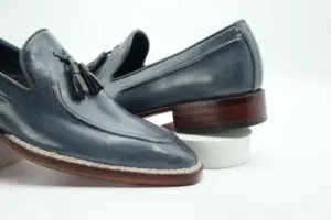 Close-up of the grey tassel loafer's leather apron seam, twin tassels and contrasting Norwegian welt stitching