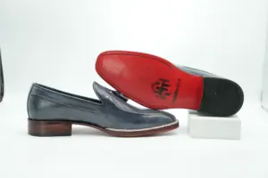 Side profile of the slate-grey tassel loafer displayed with a second shoe showing its red outsole