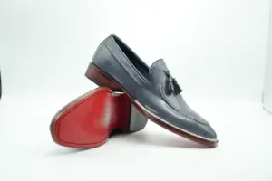 Close-up showing slate-grey Norwegian-welt tassel loafer with its contrasting red-finished sole
