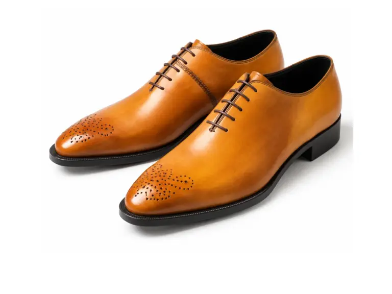 Pair of tan almond-toe Oxford dress shoes with decorative perforated toe medallions