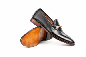 Angled black chain loafer balanced above brown leather sole