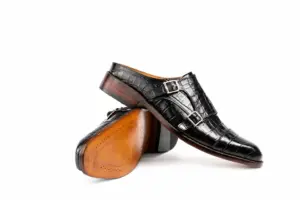 Black croc-pattern double monk mule above its warm brown finished outsole