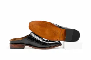 Brown branded outsole and inner side profile of a black square-toe mule