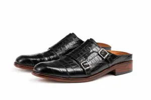 Front three-quarter view of black croc-pattern double buckle mules