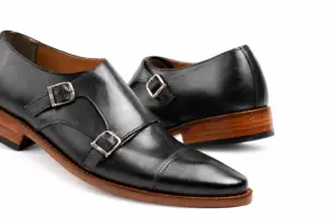 Close-up of two silver-tone buckles and black leather cap-toe seam
