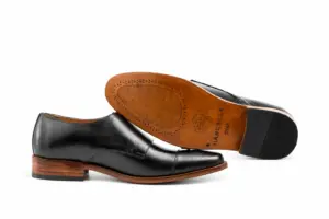 Black double monk strap shoe beside branded leather outsole
