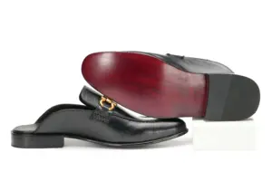 Black leather open-back mule with decorative buckle, side view