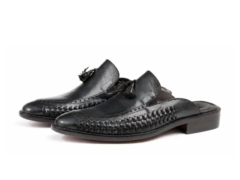 Pair of black woven-detail leather tassel mules on white background