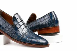 Close view of blue croc-pattern leather scales and plain loafer vamp