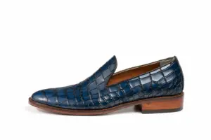 Side profile of blue croc-pattern loafer with brown sole edge and heel