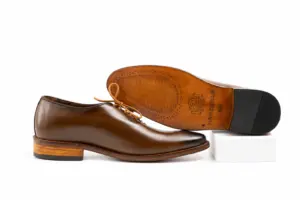 Brown wholecut Oxford side profile beside branded leather outsole