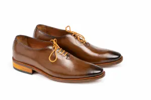 Three-quarter pair view of brown wholecut Oxfords with darkened toes