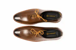 Top pair view of brown burnished wholecut Oxfords with golden-tan laces