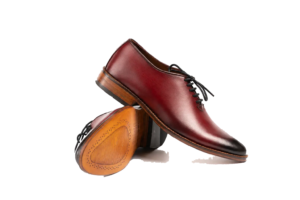 Crossed oxblood wholecut Oxfords showing the burnished toe and branded leather outsole