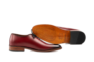 Oxblood wholecut Oxford side profile beside its brown leather outsole and black heel top lift