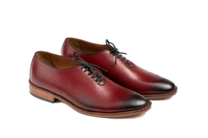 Opposite three-quarter view of oxblood wholecut Oxfords showing continuous leather uppers and black laces