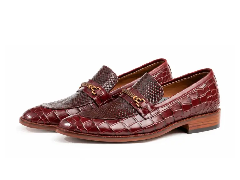 Pair of burgundy reptile-pattern horsebit loafers showing the forepart and sole profile