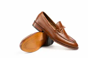 Angled cognac leather tie loafer above brown leather outsole