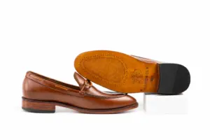 Cognac apron tie loafer profile beside branded leather outsole