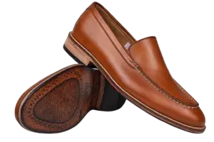 Crossed cognac apron-toe loafers showing the upper and outsole