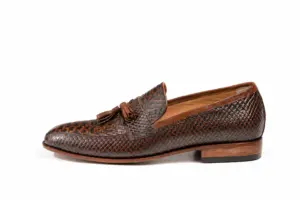 Side profile of dark brown lizard-pattern tassel loafer with low stacked-look heel