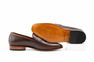 Outsole view of dark brown lizard-pattern tassel loafers with tan-brown sole and dark heel contact