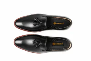 Overhead view of black wholecut tassel loafers showing the vamp and dark branded footbeds