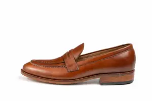 Alternate side view of brown pull-up leather penny loafer showing the leather finish and heel proportions