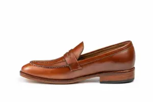 Side profile of brown pull-up leather penny loafer showing the upper shape and sole edge