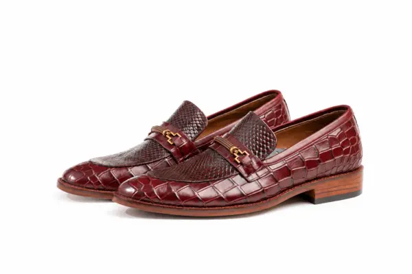 Pair of burgundy reptile-pattern horsebit loafers showing the forepart and sole profile