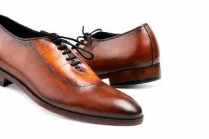 Close-up of cognac and brown croc-pattern panel cap-toe Oxford shoes showing cognac croc-pattern panel, smooth brown cap toe and black laces
