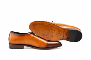 Leather outsole and dark heel top lift of cognac and brown croc-pattern panel cap-toe Oxford shoes