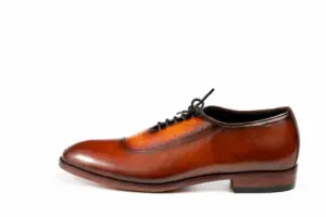 Outer side profile of cognac and brown croc-pattern panel cap-toe Oxford shoes showing the upper shape and sole edge