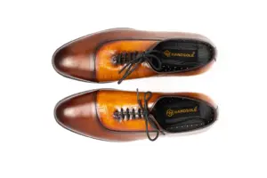 Overhead view of cognac and brown croc-pattern panel cap-toe Oxford shoes showing the vamps and HANDSOLE-branded footbeds