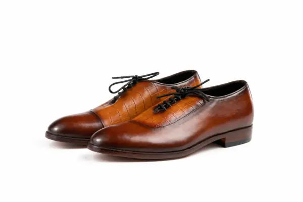Pair of cognac and brown croc-pattern panel cap-toe Oxford shoes showing the forepart and sole profile