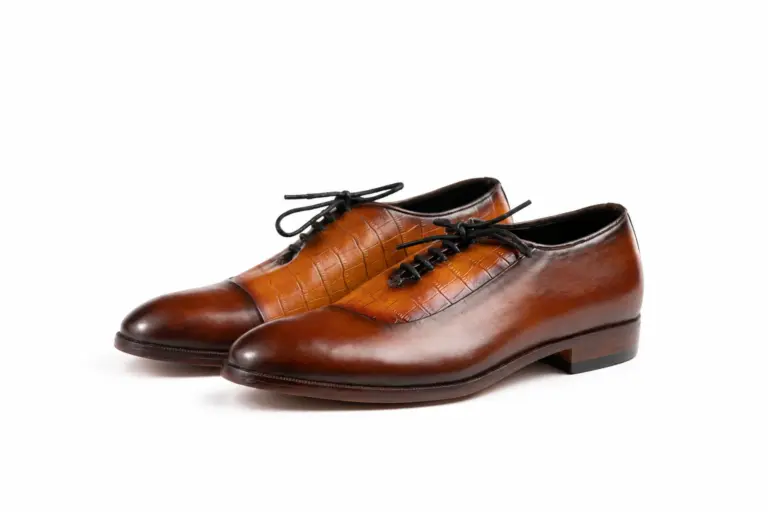 Pair of cognac and brown croc-pattern panel cap-toe Oxford shoes showing the forepart and sole profile
