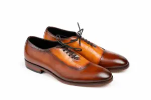 Three-quarter view of cognac and brown croc-pattern panel cap-toe Oxford shoes showing cognac croc-pattern panel, smooth brown cap toe and black laces