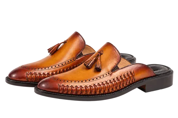 Three-quarter view of cognac tassel mules showing handwoven side panels and dark heel bases